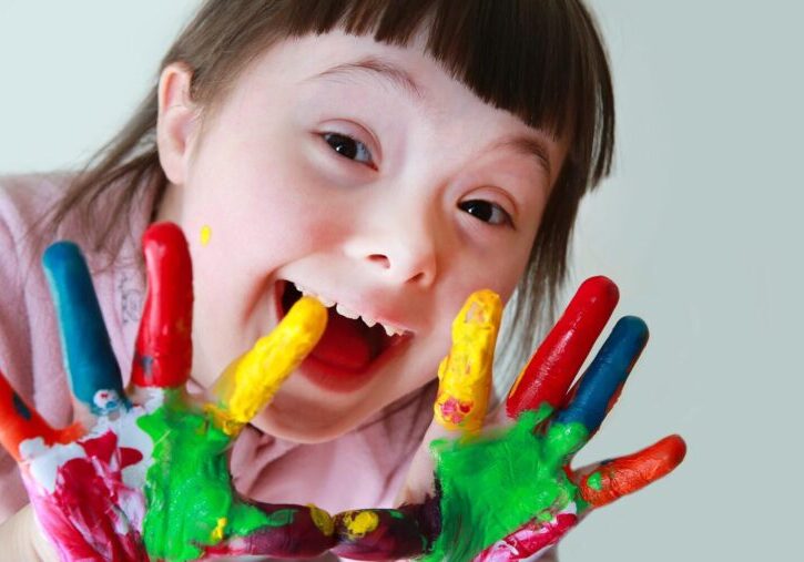 Cute little girl with painted hands. Isolated on grey background.